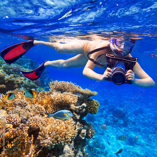 Young women snorkeling in the tropical water with camera