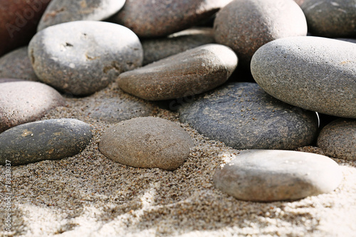 Gray sea pebbles on sand background