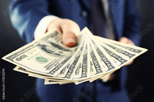 Cuadro en lienzo Businessman giving money on dark background