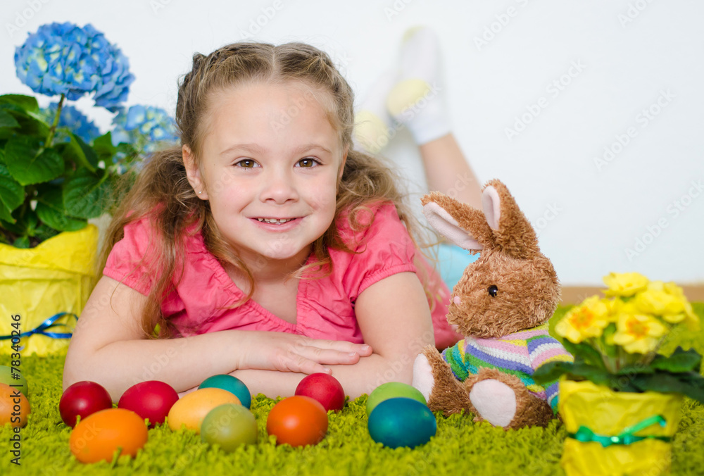 Smiling little girl lying with Easter eggs on green carpet Smiling little girl lying with Easter eggs on green carpet
