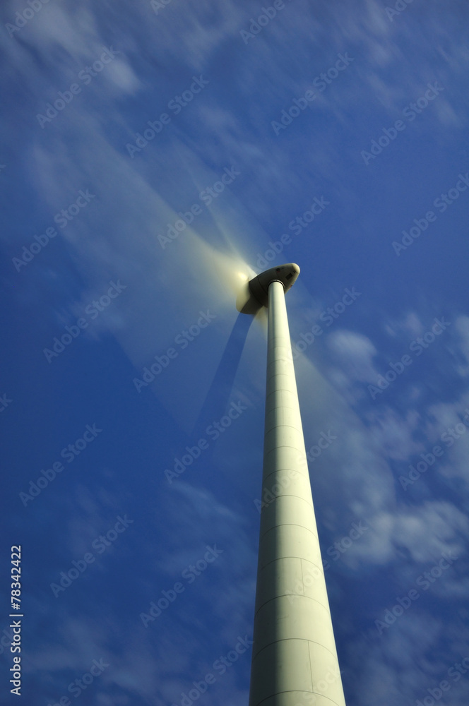 Eolienne en mouvement sur fond de ciel bleu et nuages blancs Eolienne en mouvement sur fond de ciel bleu et nuages blancs