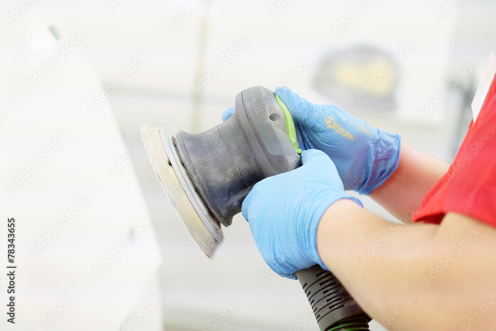 Painter polishes a car body component