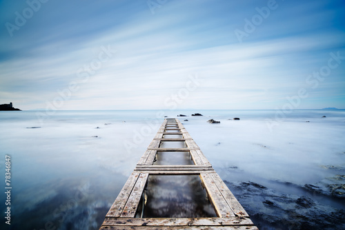 Wooden pier or jetty on a blue ocean in the morning.Long Exposur