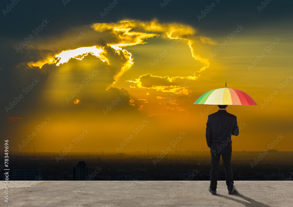 Businessman standing behind with multicolor umbrella looking Ban