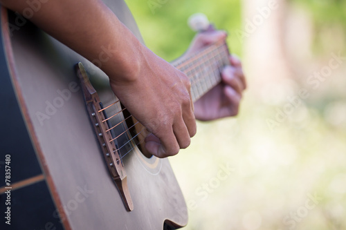 Male hand playing acoustic guitar on meadow background © pingpao