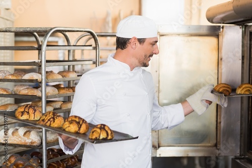 Smiling baker holding trays of croissants
