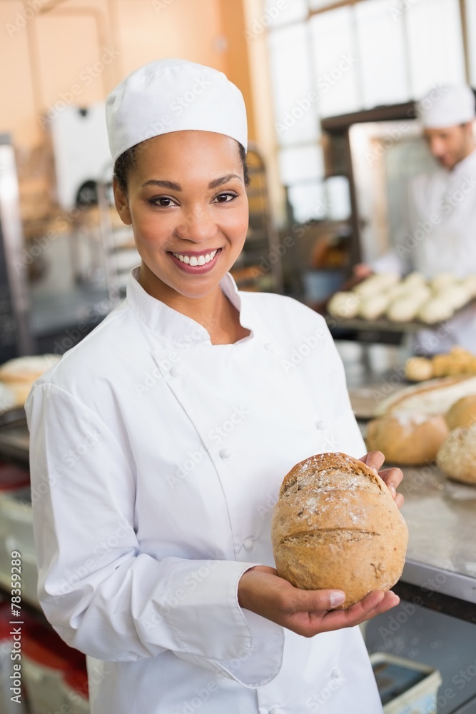Pretty baker smiling at camera with loaf Pretty baker smiling at camera with loaf