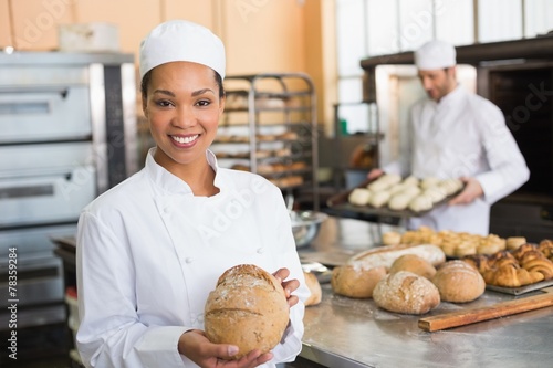 Fotografia Pretty baker smiling at camera with loaf