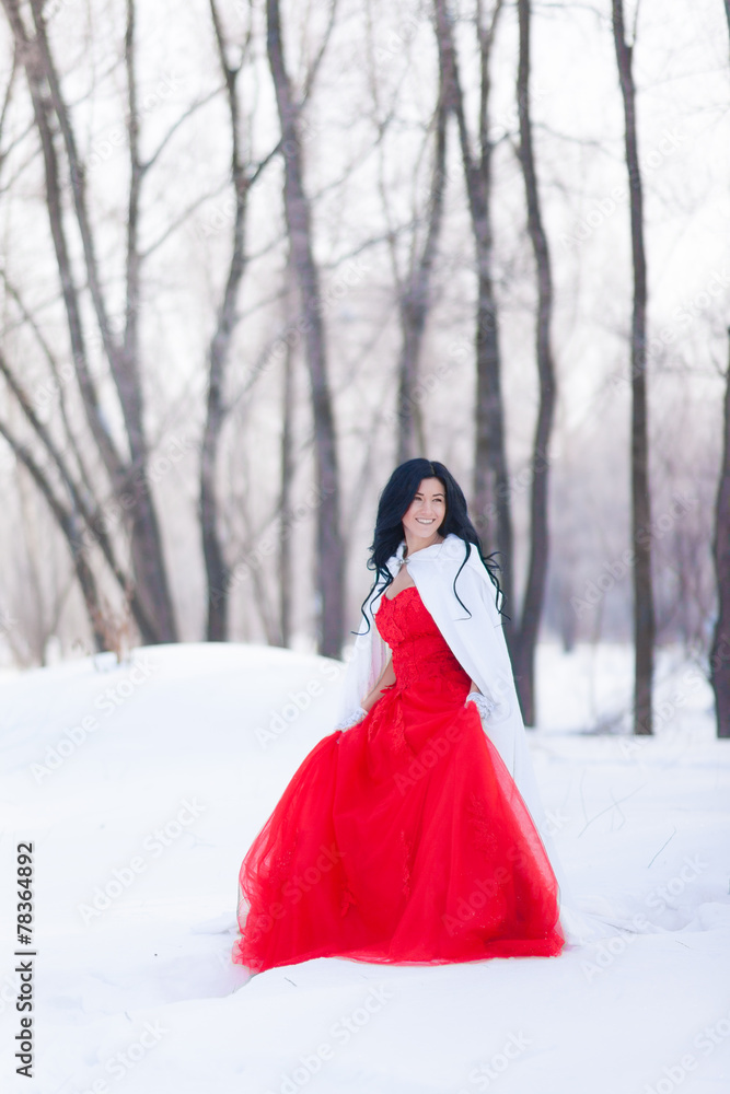 Brunette in a red dress in the winter forest. Brunette in a red dress in the winter forest.