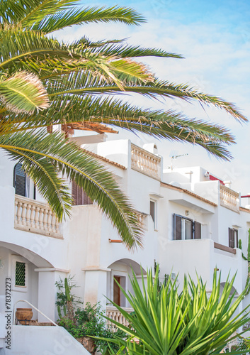 Portrait of tropical apartment building with trees.