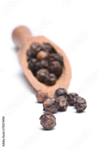 black peppercorns on a wooden scoop isolated on white