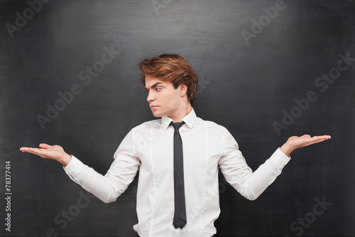 Man with palms up making a choice on chalkboard background