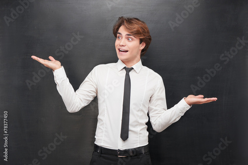 Surprised man with one palm above on chalkboard background