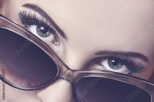 Seductive woman closeup portrait looking over sunglasses