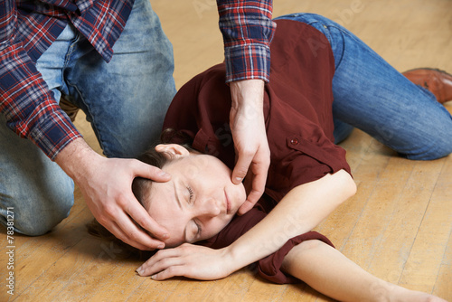 Fotografie Man Placing Woman In Recovery Position After Accident
