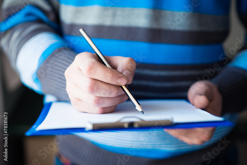 businessman holding a clipboard and write on it