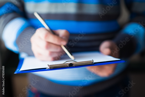 businessman holding a clipboard and write on it