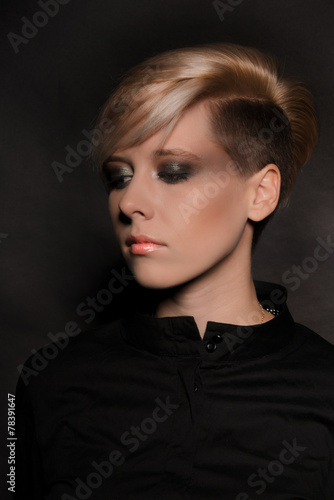 Blonde girl with a short stylish haircut on a dark background  