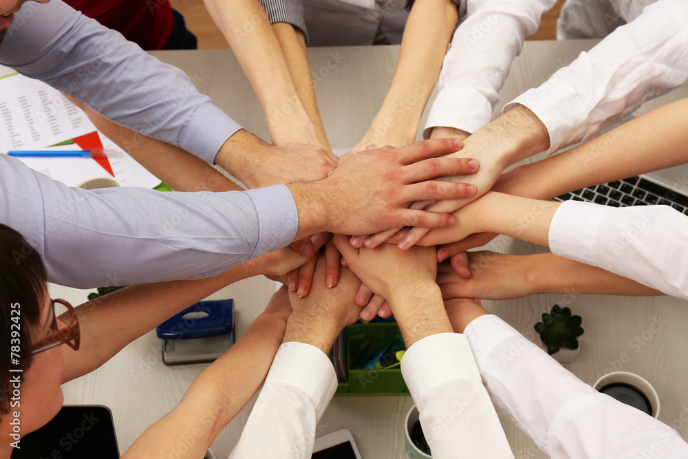 United hands of business team on workspace background top view United hands of business team on workspace background top view