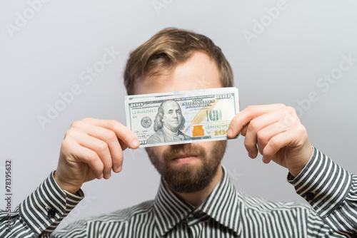 Businessman with a dollar bill blinding his eyes
