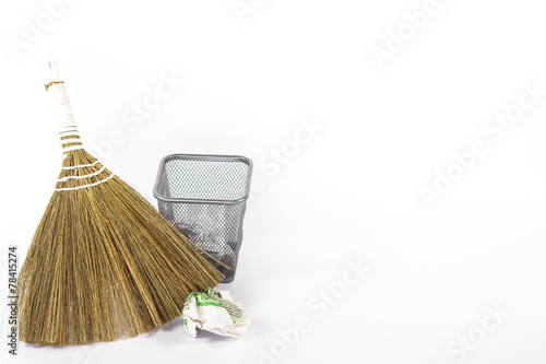 isolated broom and wastebasket full of waste newspaper