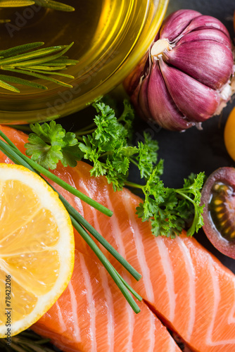 Portion of fresh salmon and herbs on black background photo