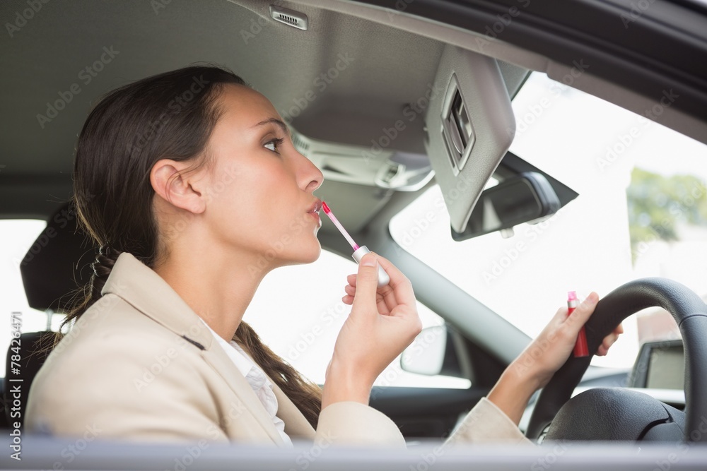 Businesswoman using mirror to put on lip gloss Businesswoman using mirror to put on lip gloss