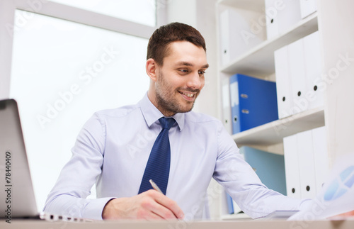 businessman with laptop and papers in office