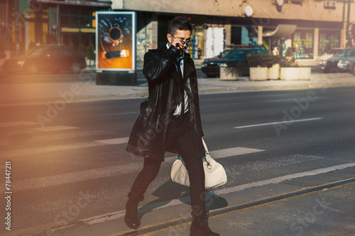 man in a leather coat and sunglasses crossing the road