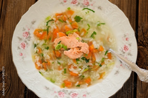 Homemade fish soup with rice and carrot on wooden background