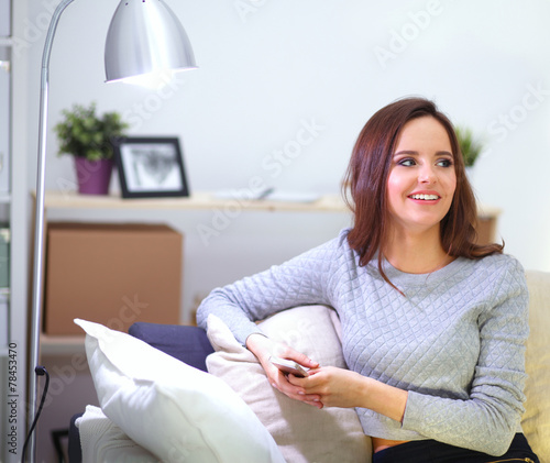Pretty girl using her smartphone on couch at home in the living