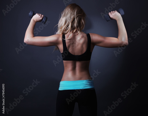 Sport back of atletic woman with dumbbells.