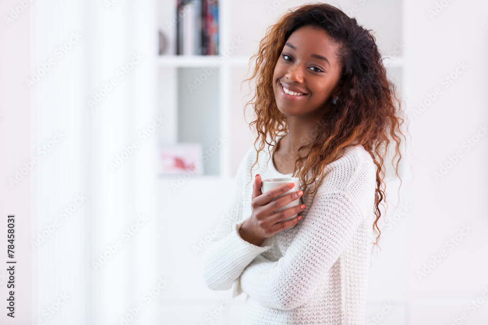 African American woman in her living room drinking holding a cof African American woman in her living room drinking holding a cof