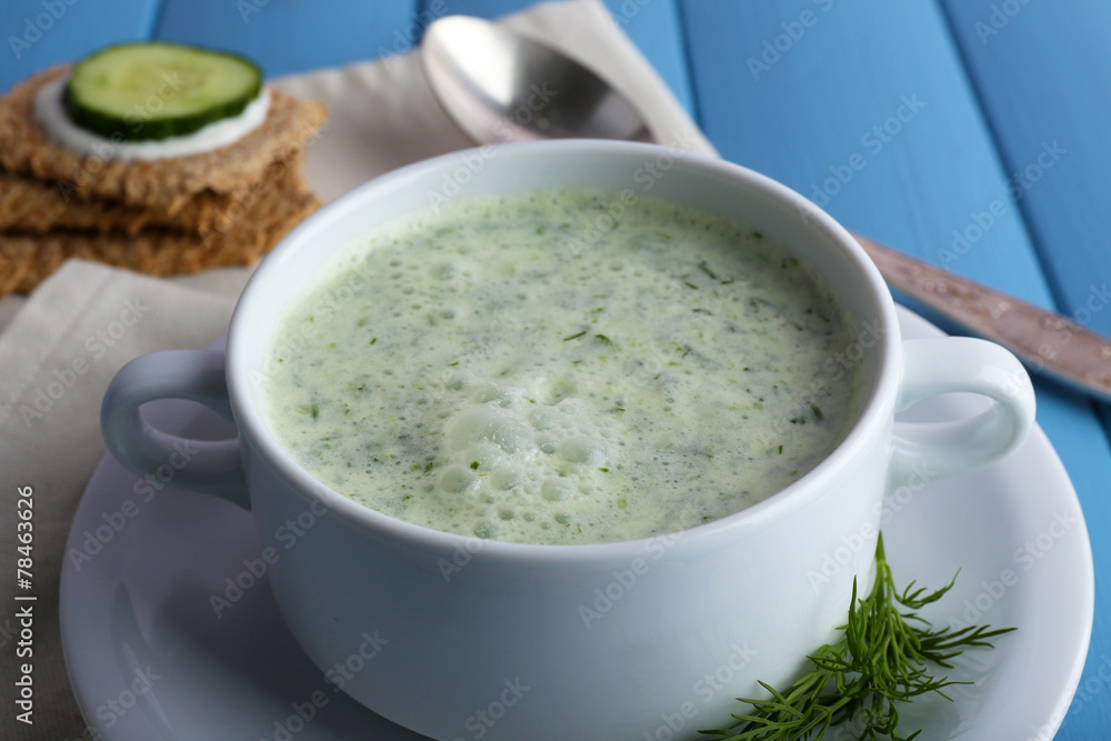 Cucumber soup in bowl on color wooden planks background Cucumber soup in bowl on color wooden planks background