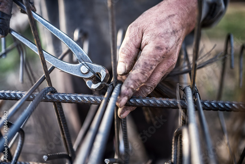 Photo Details of construction worker - hands securing steel bars