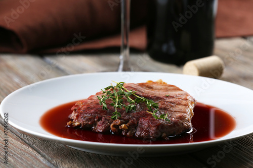 Grilled steak in wine sauce with bottle of wine