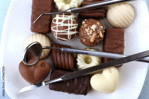 Dentist tools with sweets on plate close up