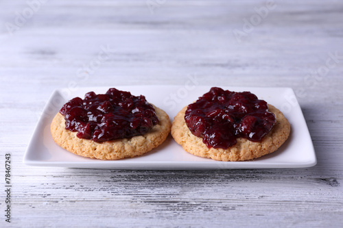 Delicious cookies with jam on plate on wooden background