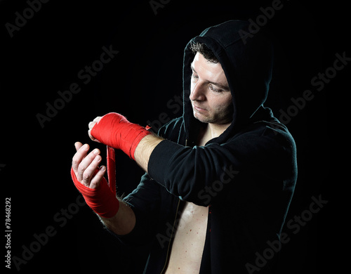 fighter man in boxing hood wrapping hands before fight