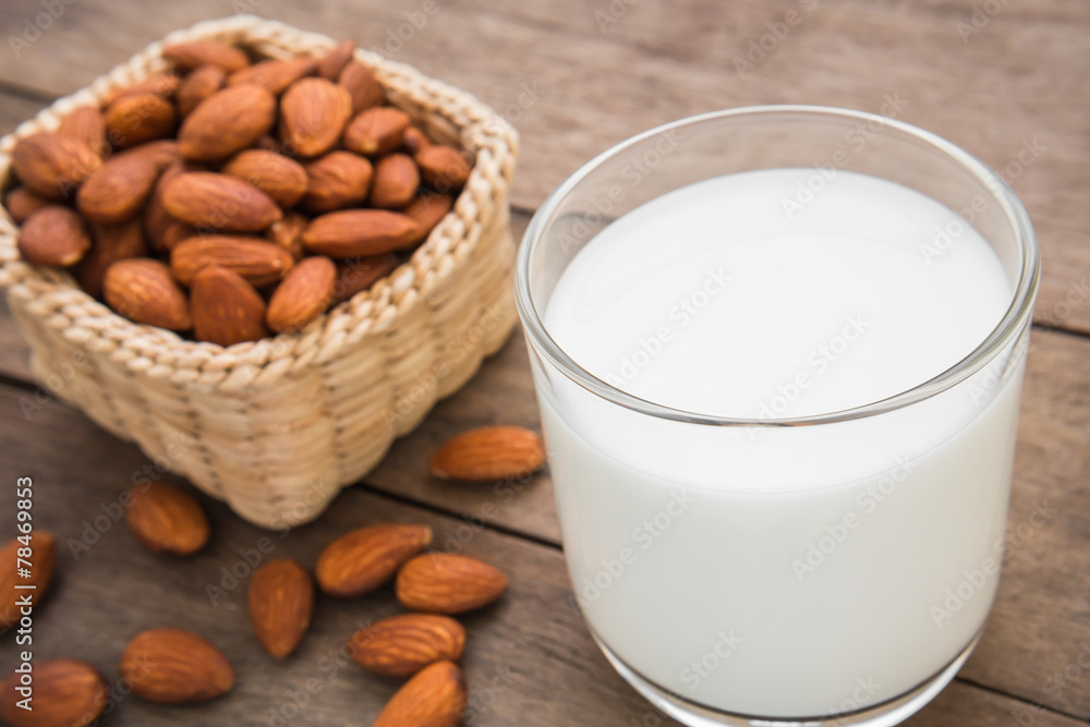 Almond milk in glass with almonds on wooden table Almond milk in glass with almonds on wooden table