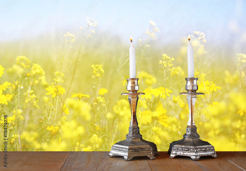 two candlesticks with burning candles over wooden table and flow two candlesticks with burning candles over wooden table and flow