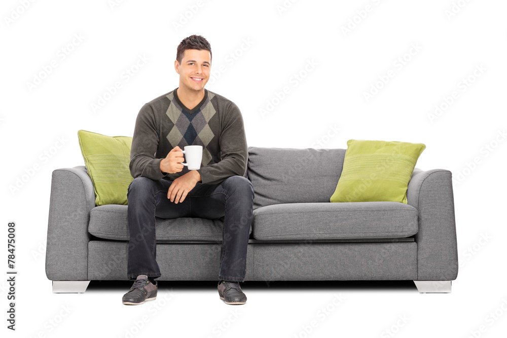 Man holding a cup of coffee seated on sofa Man holding a cup of coffee seated on sofa