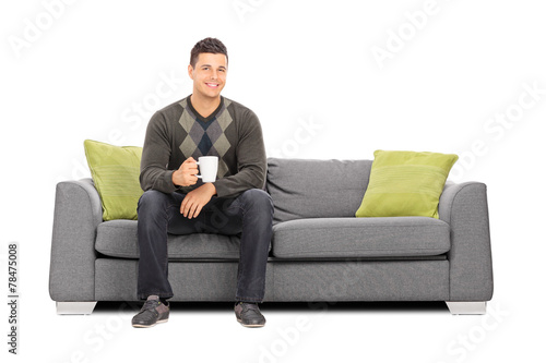Man holding a cup of coffee seated on sofa