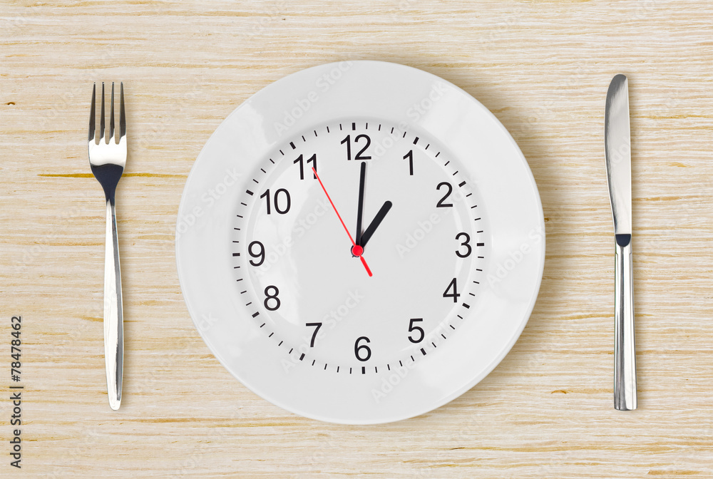 Dinner plate with clock face on wooden table Dinner plate with clock face on wooden table