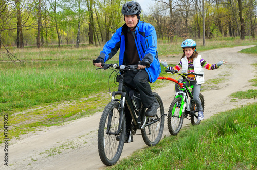 Happy family on bikes, father cycling with kids outdoors