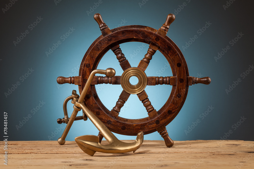 Obraz premium maritime adventure anchor and old wooden steering wheel