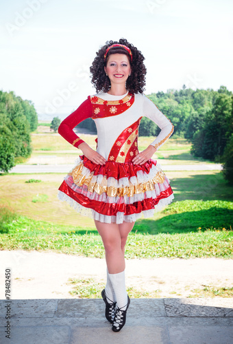 Young woman in irish dance dress and wig posing outdoor photo