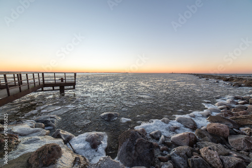 sunset over frozen sea with old metal bridge