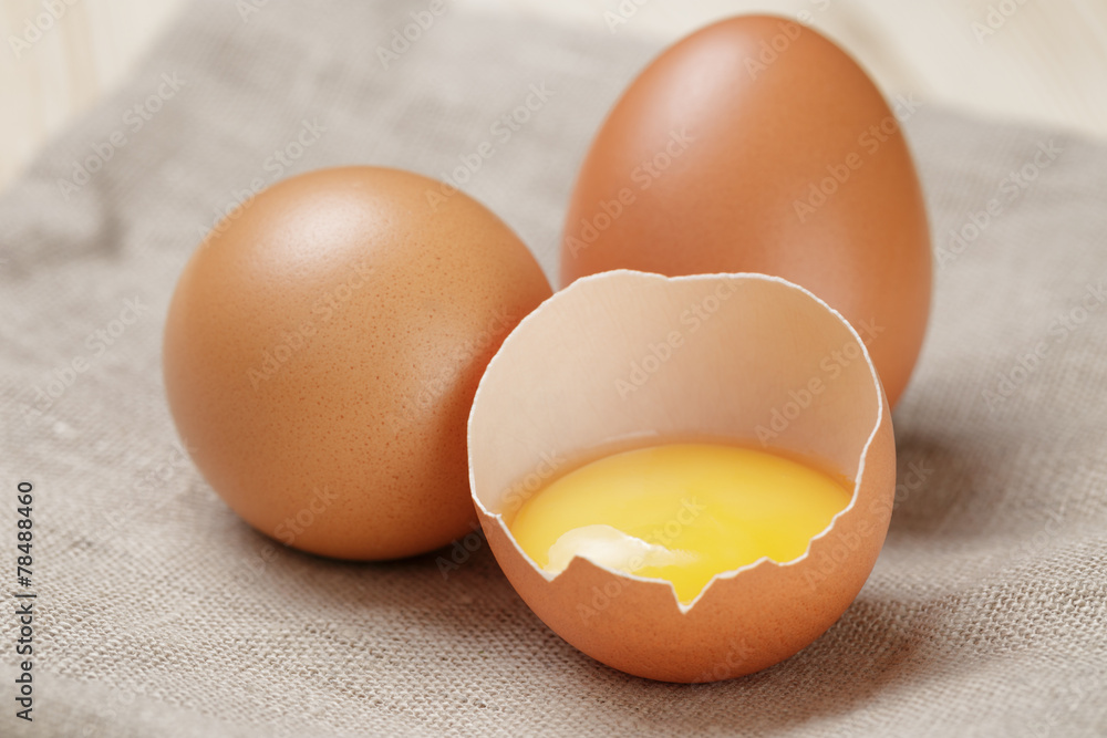 whole and broken raw brown eggs closeup on wood table whole and broken raw brown eggs closeup on wood table