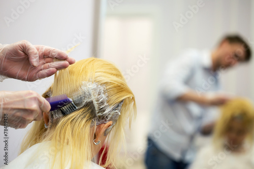 A hairdresser dyeing hair for a blonde girl